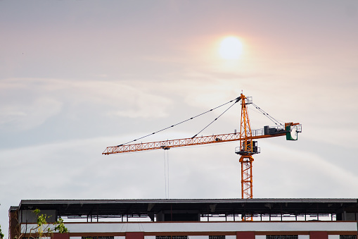 about the tower crane at some of the construction sites when sunset that is used for building the city town