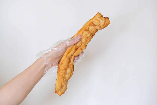 Woman's hand holding Chinese fried dessert .Youtiao.