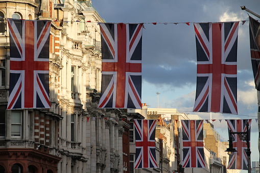 Some Union Jack flags in London waving on a building in sunlight