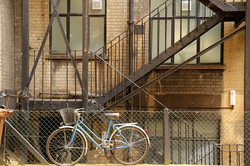 A blue bicycle parked near an outdoor staircase in front of a home