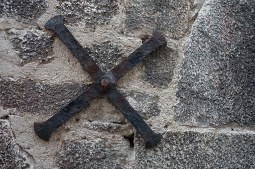 Detail of the old wrought iron cross bracing supporting the stone facade of an old medieval house