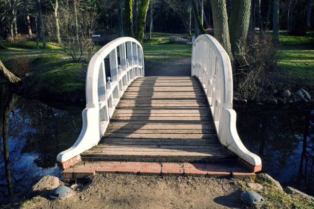An old wooden white bridge over a pond.