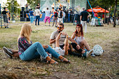 Group Of People Sitting On A Grass And Talking At The Music Festival