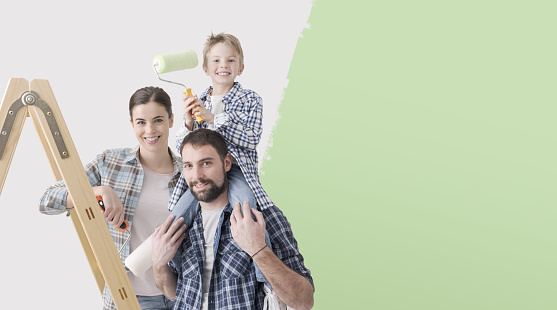 Happy family with kid painting their new house, renovation and home makeover concept