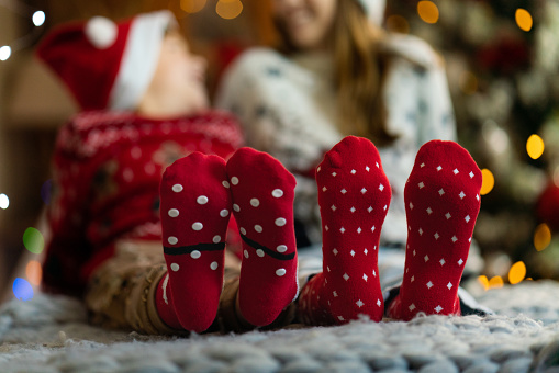 Close-up of cute kids in Christmas socks sitting in a cozy Christmas atmosphere. Focus in on legs