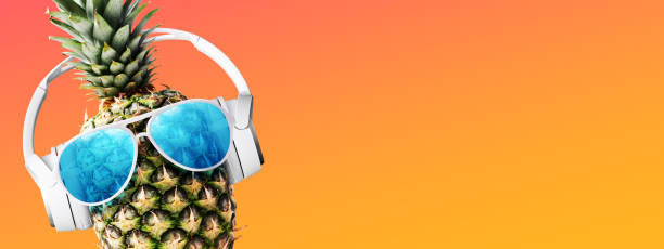Happy pineapple wearing sunglasses and headphones, it is listening to music, summer and party concept