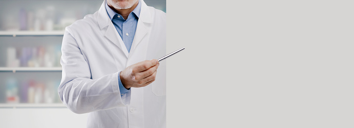 Doctor showing a blank white sign and pointing with a pen, he is giving medical advice