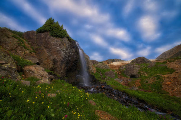 Mountain waterfall with rocks and trees at sunset