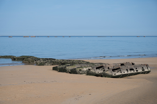 Detail of a fragment of the Mulberry artificial port from Operation Overlord D-Day. It is half buried and stuck on the beach, it is full of moss