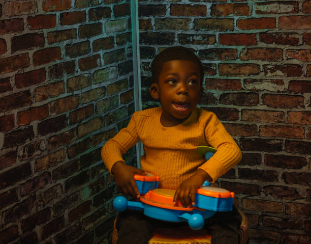 African American child playing with friend in brick-walled room
