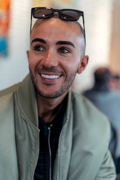 istock Young man in a green jacket smiling with sunglasses on head 2062881179
