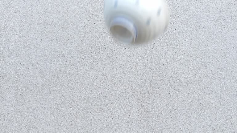 Throw a white porcelain cup against a cement wall.