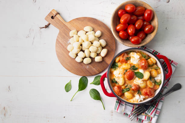 istock Creamy gnocchi with tomato sauce, spinach and mozzarella on a white wooden table 2062887217