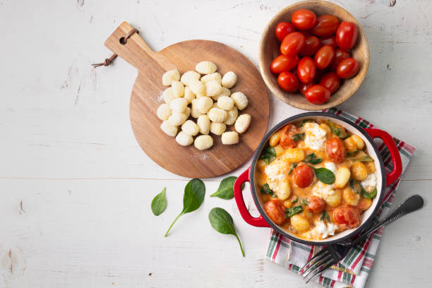 Creamy gnocchi with tomato sauce, spinach and mozzarella on a white wooden table - fotografia de stock