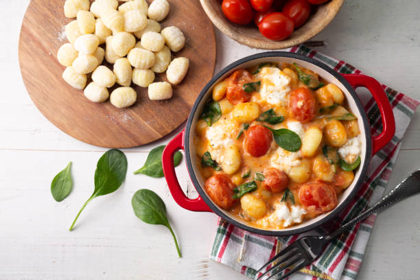 Top view of gnocchi in creamy tomato sauce with spinach and melted mozzarella on a white background - fotografia de stock