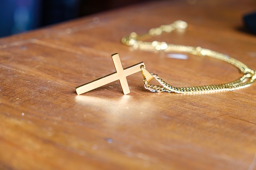 A golden cross necklace on a wooden table