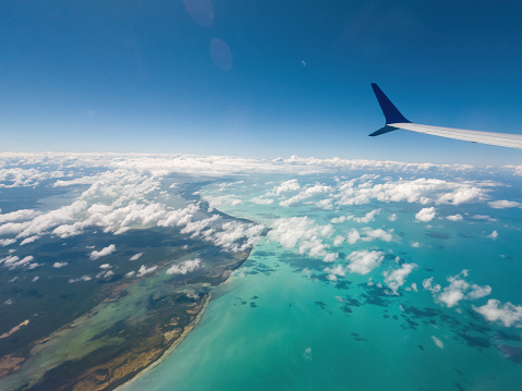 An airplane wing soaring over blue ocean and clouds