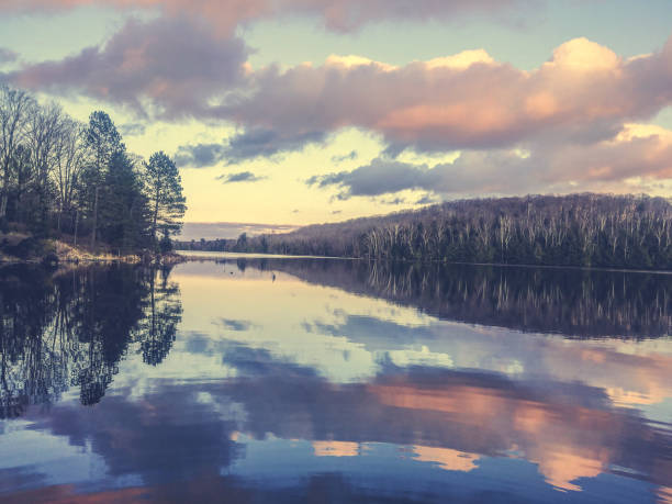 Tranquil lake under spring sunset sky with trees yet to bloom
