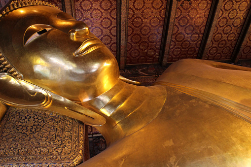 A giant golden statue lying on the ground beside two other statues