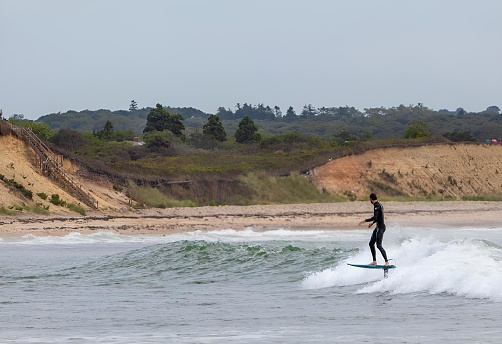 Chilmark, United States – August 24, 2022: A surfer enjoying a late summer swell of big waves off the coast of Martha's Vineyard