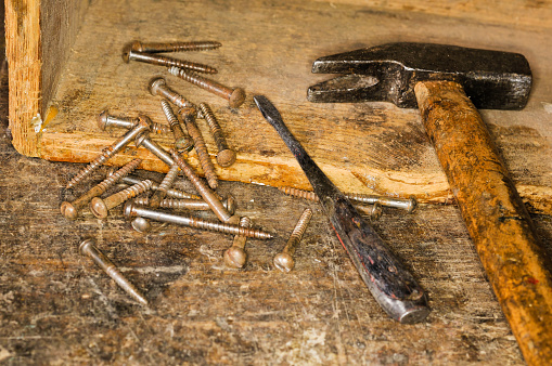 A Hammer, screws, screwdriver and wooden box arranged on a workbench