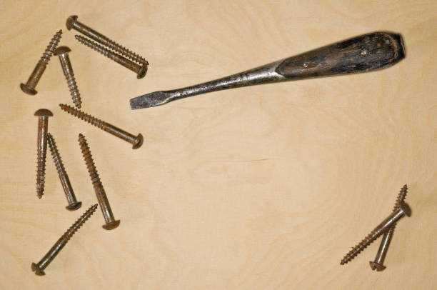 istock Screws and a screwdriver on a wooden board 2062934414