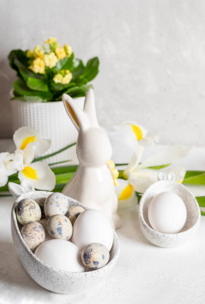 istock White holiday decorations on Easter table. Eggs in bowls with bunny ears, ceramic bunny, flowers. 2062941535