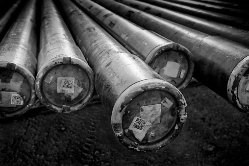 A black and white photograph of drilling pipe for an oil rig