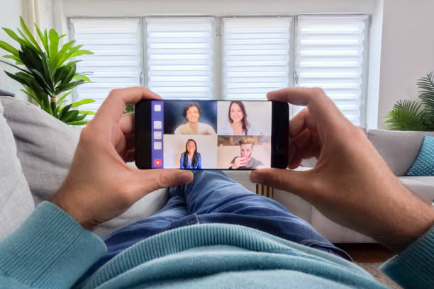 joven teniendo una videollamada con amigos mientras está acostado en el sofá de casa - young women sitting simple living eastern europe fotografías e imágenes de stock