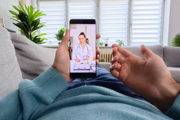 istock Young Man Having A Doctor's Appointment Online Using Smart Phone On The Sofa At Home 2062954137