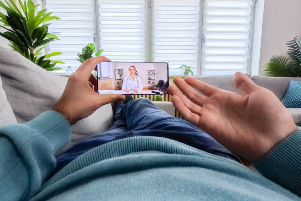 istock Young Man Having A Doctor's Appointment Online Using Smart Phone On The Sofa At Home 2062957921