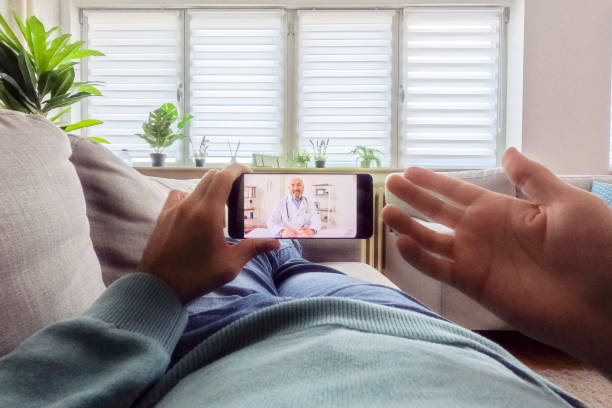 istock Young Man Having A Doctor's Appointment Online Using Smart Phone On The Sofa At Home 2062970062