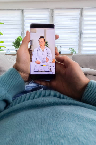 istock Young Man Having A Doctor's Appointment Online Using Smart Phone On The Sofa At Home 2062972197