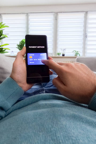 istock Young Man Putting In Credit Card Info Into His Smart Phone While Shopping Online 2062974332