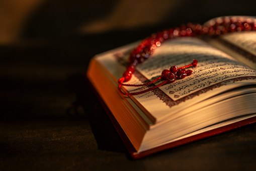 Holy book Quran and rosary beads on dark background