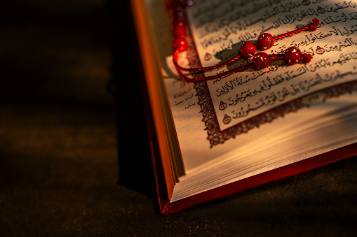 Holy book Quran and rosary beads on dark background