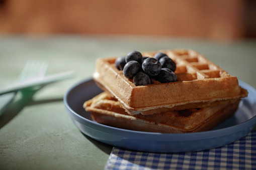 Two waffles with blueberries on a blue plate
