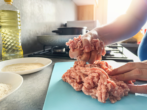 women's hands preparing tasty cutlets  raw chicken mince at home kitchen. Uncook raw food