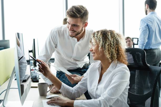 istock Two employees in a modern office, a man and a woman working at a computer, colleagues discussing and consulting, thinking about a joint project 2063089637