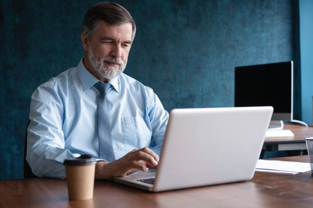 istock Mature business man executive manager looking at laptop computer watching online webinar training or having virtual meeting video conference taking notes, doing market research working in office. 2063089868