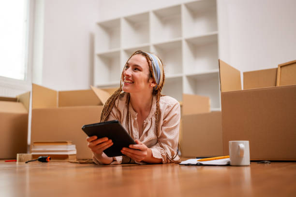 Happy ginger woman using digital tablet  in her new home - foto de acervo