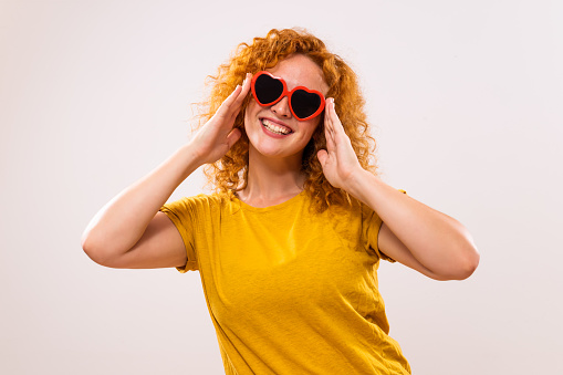 Image of happy  ginger woman with red heart shaped sunglasses.