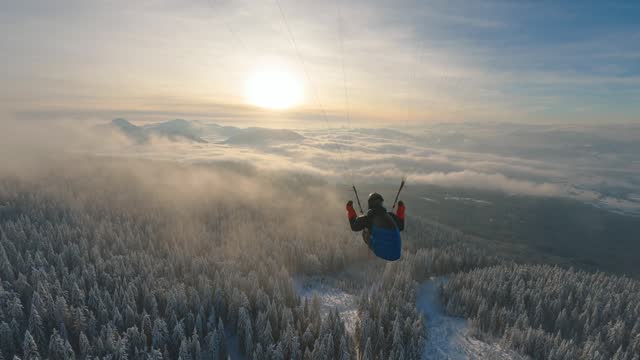 Dream flying paragliding above foggy clouds in winter forest nature, freedom adrenaline adventure