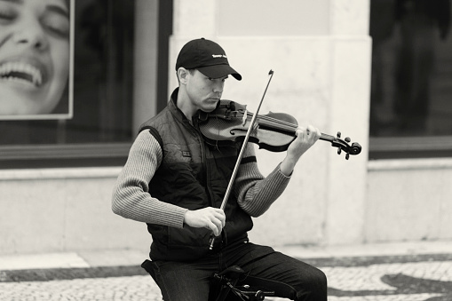 Lisbon, portugal - December 9, 2023: A street musician plays a violin at the Rua Augusta street in Lisbon downtown.