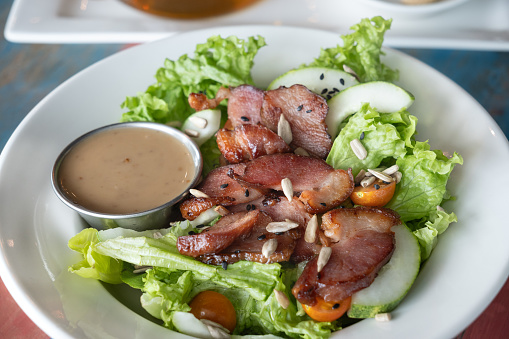 A bowl of smoked duck salad accompanied by roasted sesame dressing.