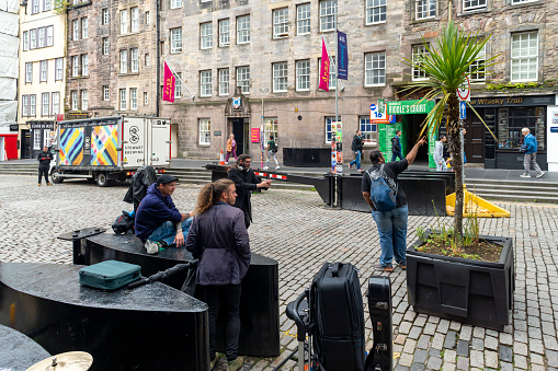 Royal Mile, Edinburgh, Scotland, August 2023. This is the Royal Mile early morning during the Edinburgh Fringe Festival.  There are tourists on the street looking at shops etc.