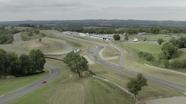 Vintage car racing on Pau-Arnos circuit as seen from drone flying. Aerial forward