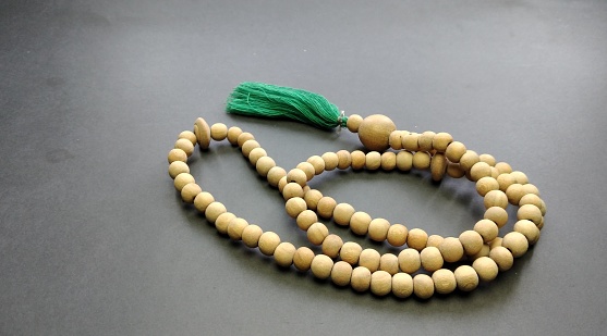 Wooden rosary beads with green thread on black background.