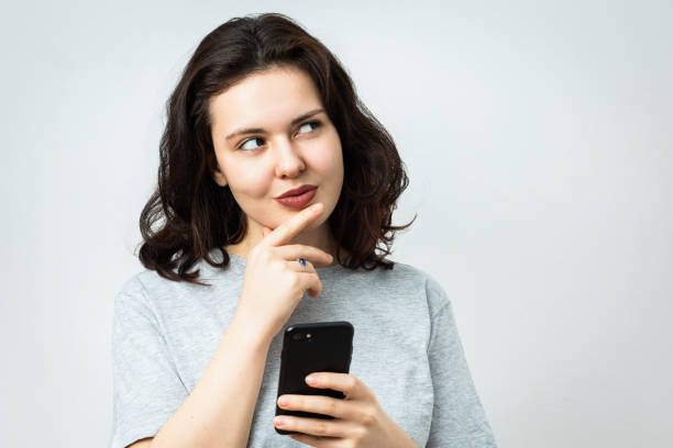 istock Beautiful young girl with phone looking aside 2063166226