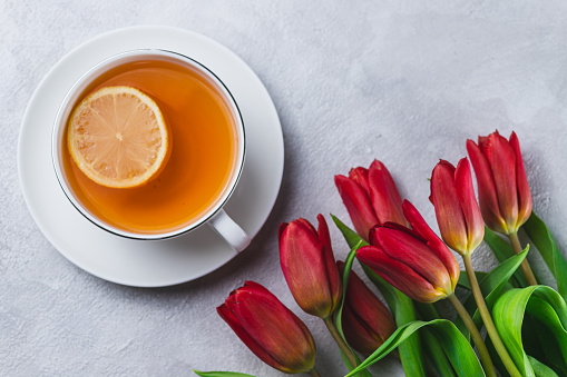 A mug of tea with a slice of lemon and a bouquet of tulips